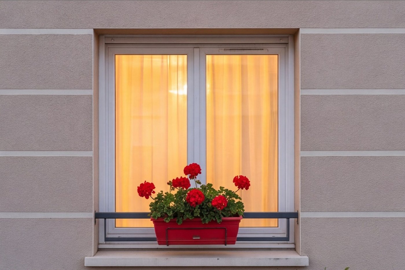 Fenêtre éclairée de la résidence R01 et sa jardinière de géraniums, illustration non contractuelle